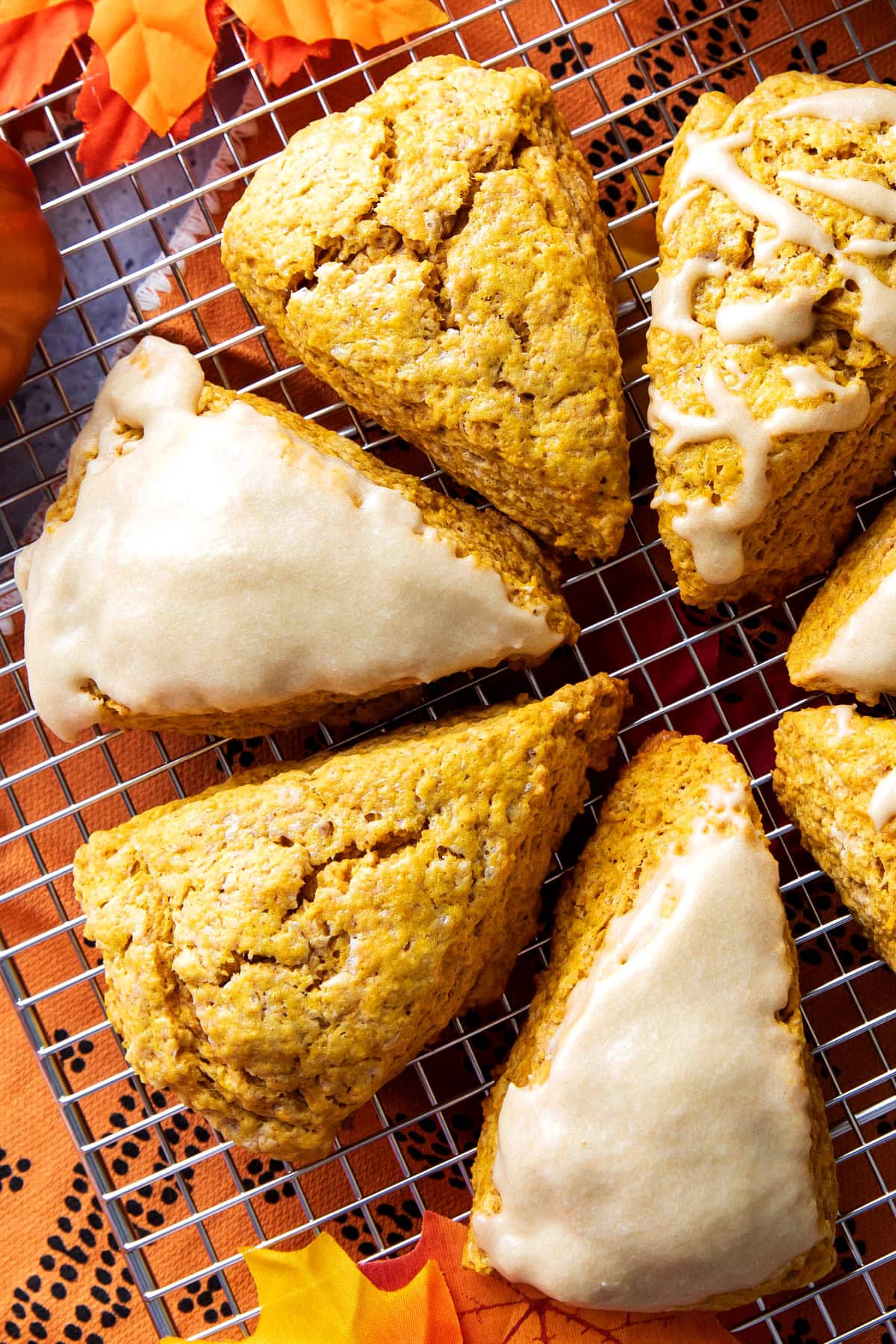 Close up of the flaky, cracked tops of fresh-baked pumpkin scones with maple glaze