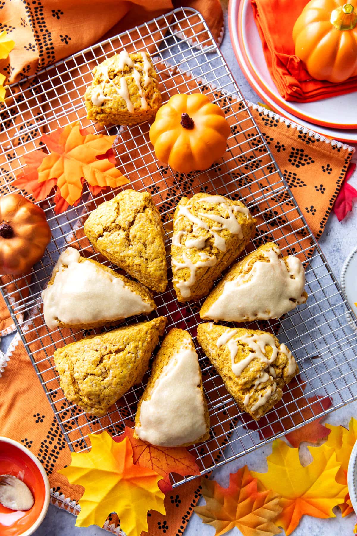 Overhead photo of easy pumpkin scones on a cooling rack with some topped with coarse sugar and other with maple glaze