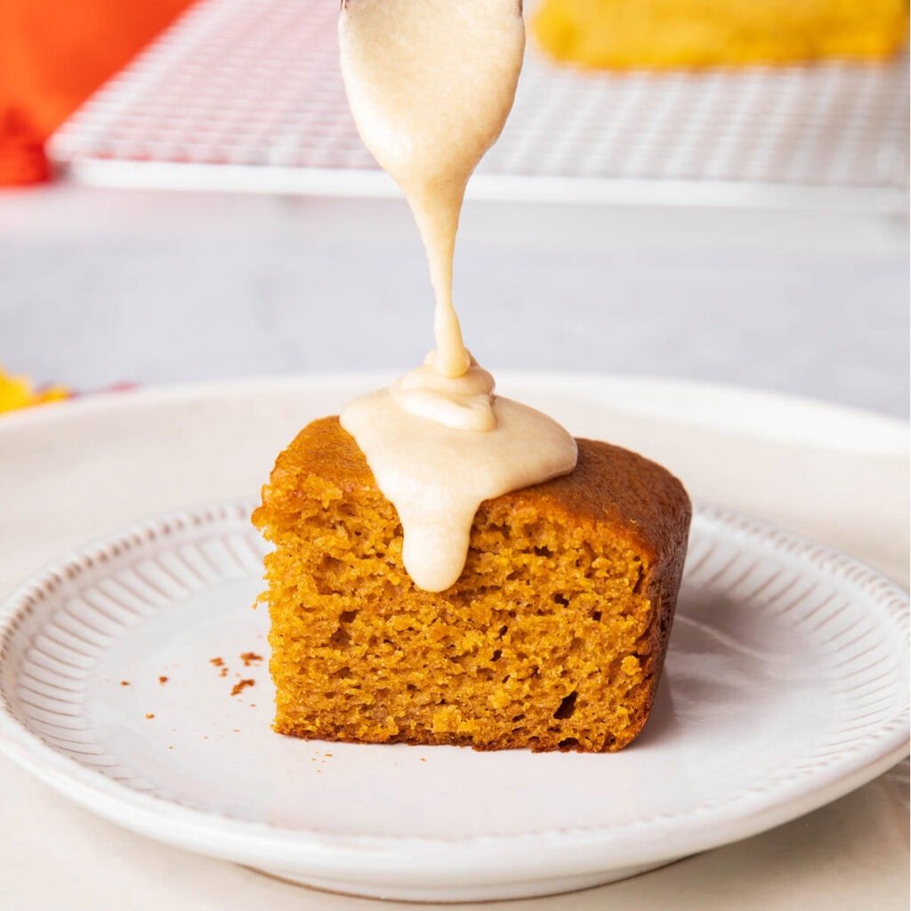 Pouring a spoonful of maple glaze over a pumpkin dessert