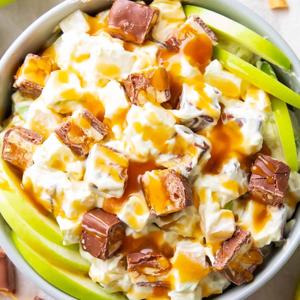 close up of caramel drizzle over snickers salad and granny smith apples