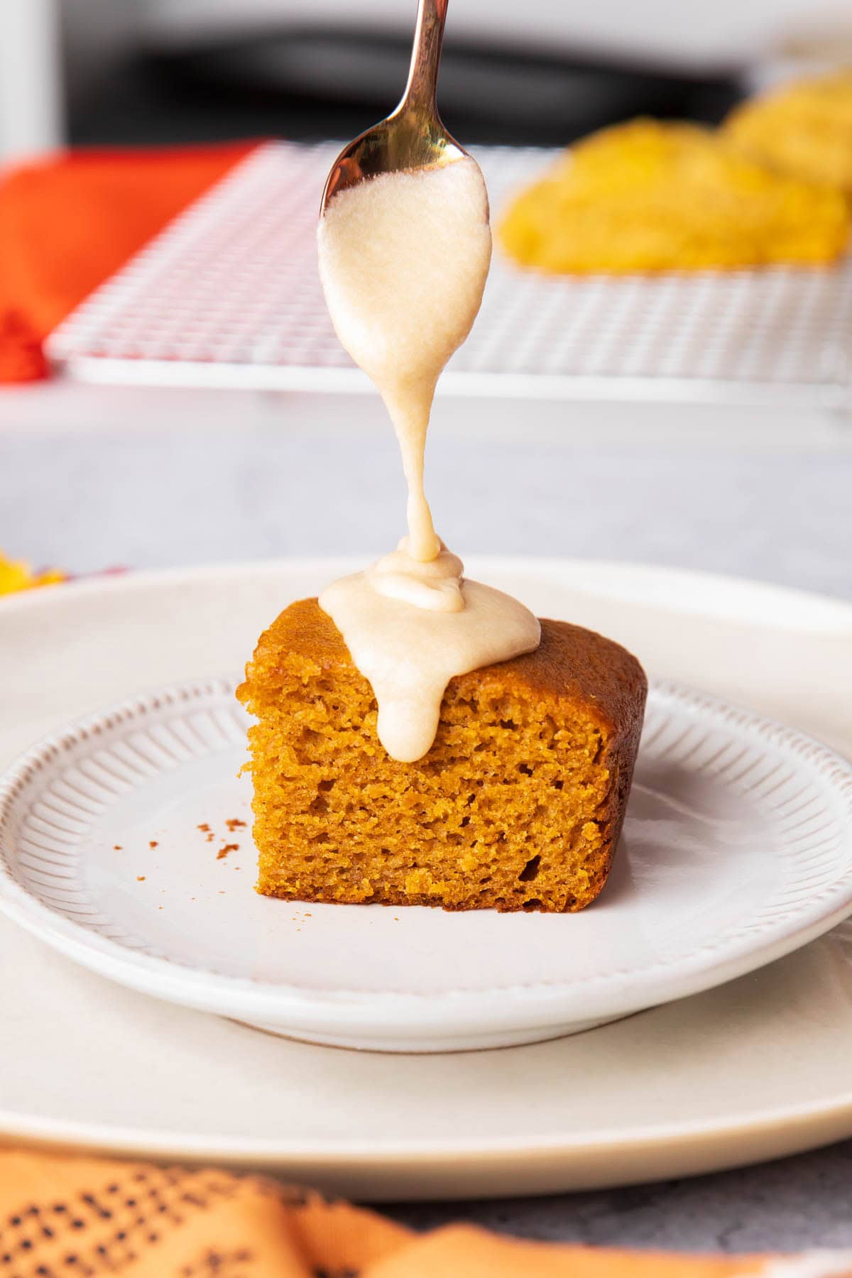 Spoon drizzling onto Pumpkin Cake - drizzling this sweet maple glaze thickly over a dessert