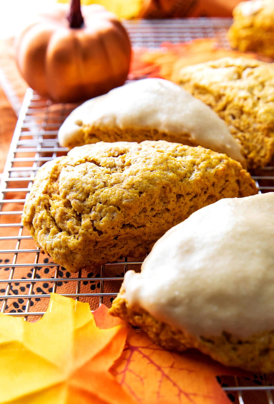 Close up of this easy pumpkin scones recipe shows crumbly edges and a shiny top from the heavy cream brushed on top before baking