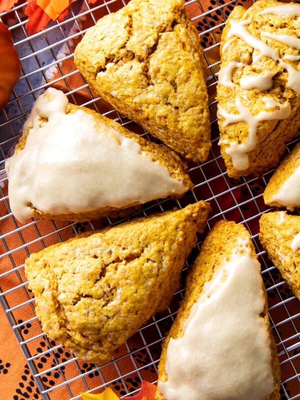 Close up of the flaky, cracked tops of fresh-baked pumpkin scones with maple glaze