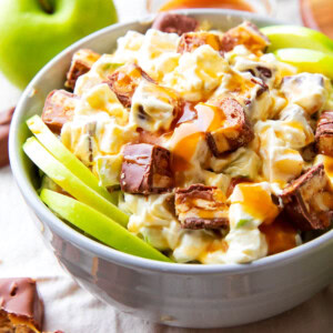 Snickers apple salad with Cool Whip served with Granny Smith apple slices and caramel apple topping