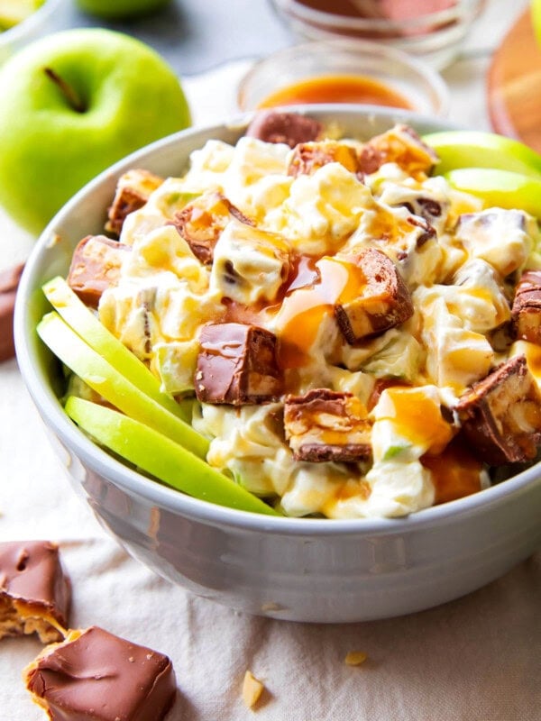Snickers apple salad with Cool Whip served with Granny Smith apple slices and caramel apple topping