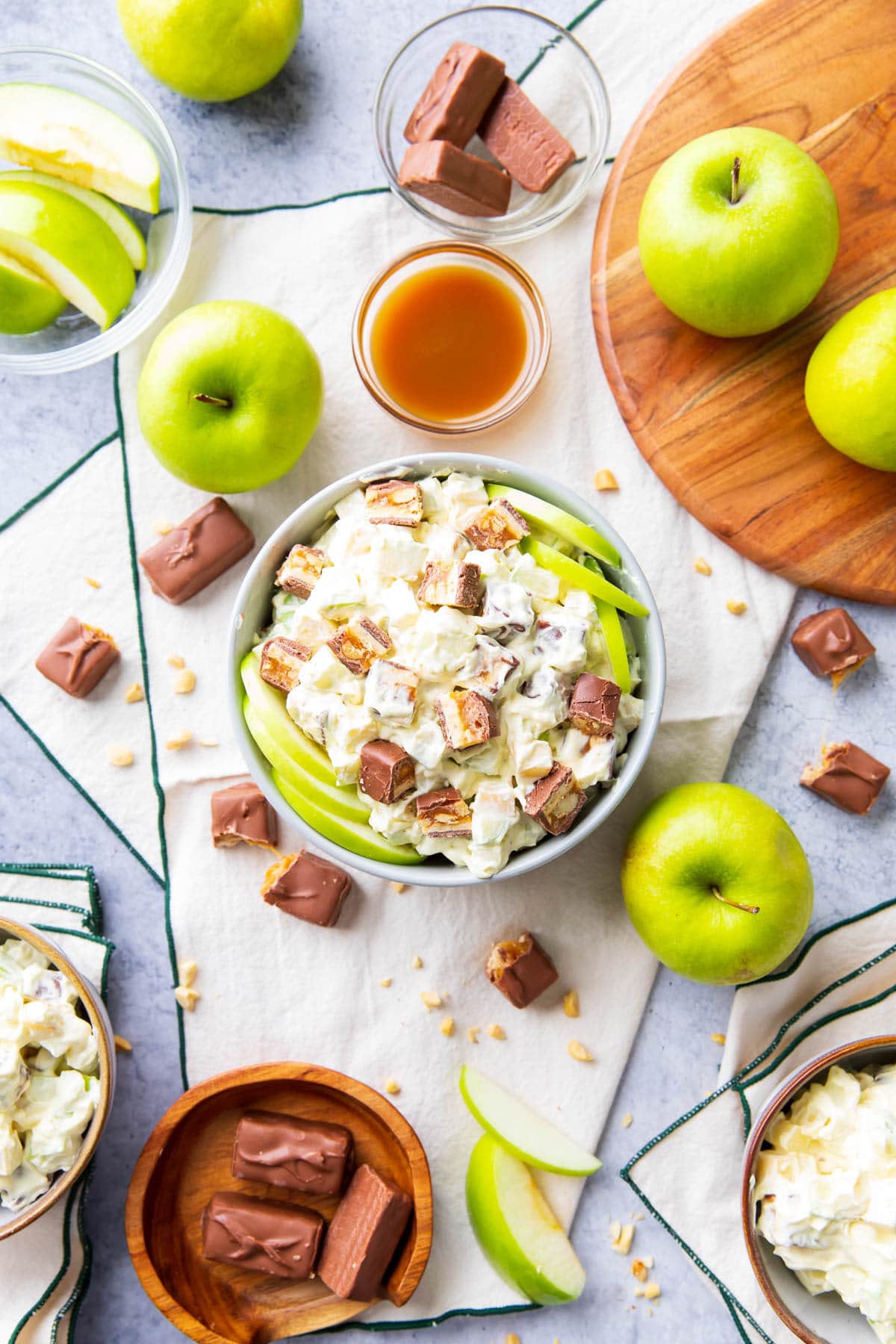 A table covered in apples, caramel sauce, candy, and this fruit salad recipe