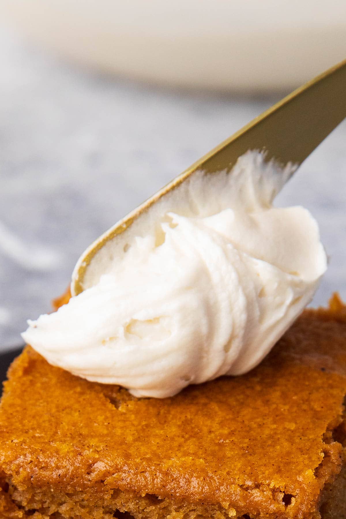 Dollop on gold spreader onto pumpkin cake - spreading a dollop of icing onto a slice of cake