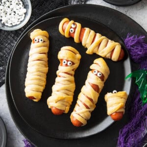 spooky halloween table set with this hot dog mummies recipe, purple and black gauze, and a spiderweb dipping sauce