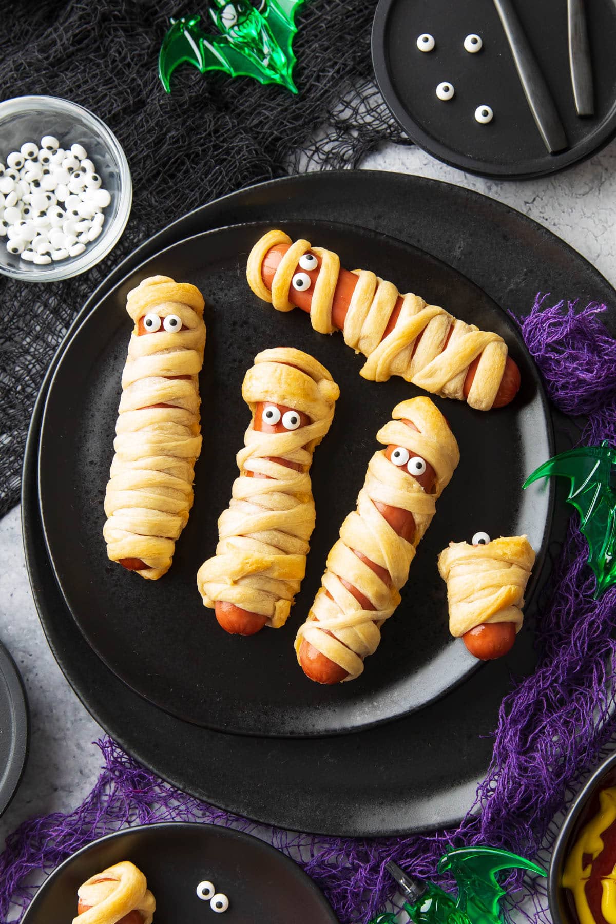 Mummy hot dogs are wrapped in crescent roll dough, baked, then dotted with googly eyes