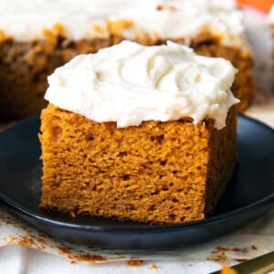 A slice of easy pumpkin cake served on a plate with lots of frosting