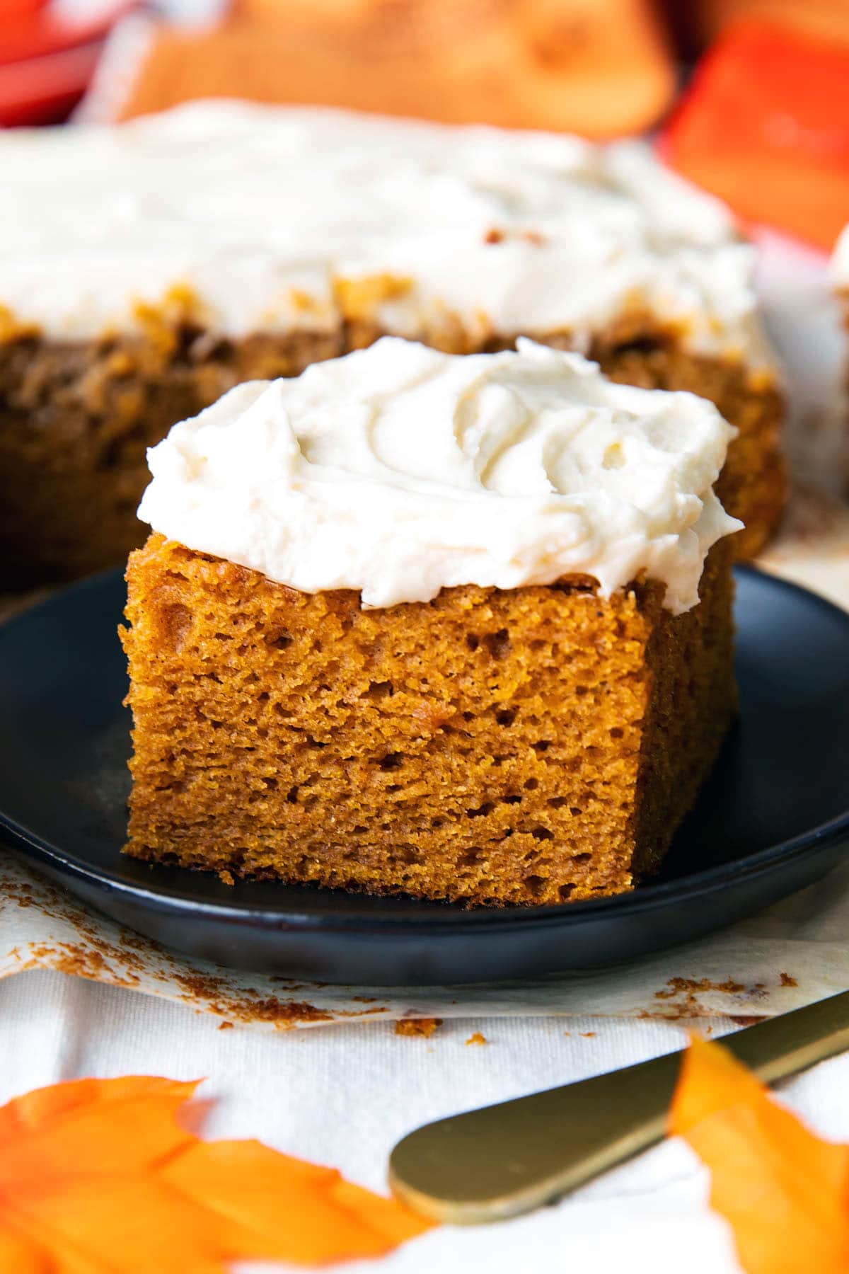 A slice of pumpkin cake served on a plate with piles of frosting.