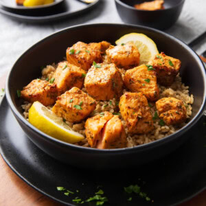 Air Fryer Salmon Bites in black bowl over a bed of rice.