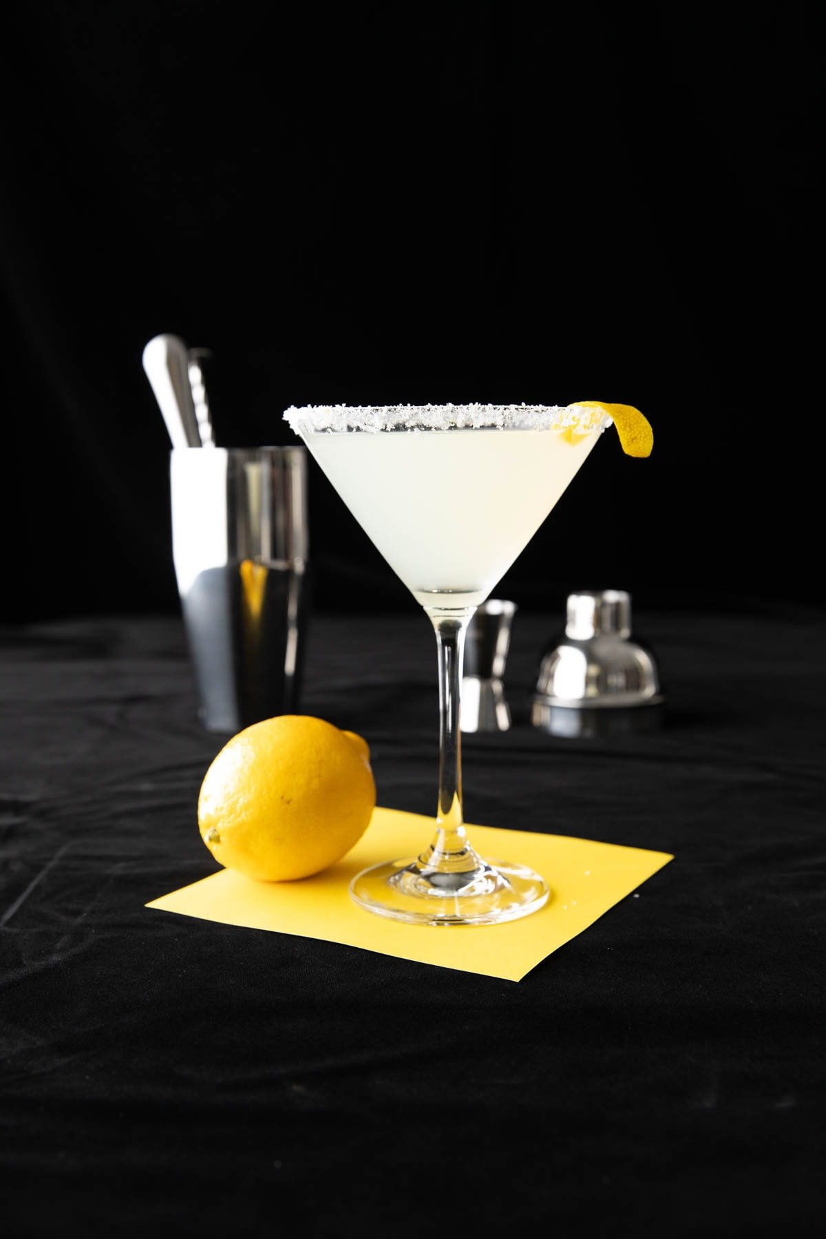 Serving this cocktail recipe in a cocktail glass with a sugar rim and a cocktail set behind it.