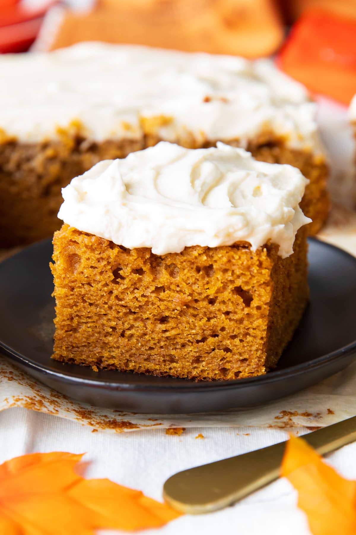 A slice of pumpkin cake with cream cheese frosting that’s moist with a tender crumb