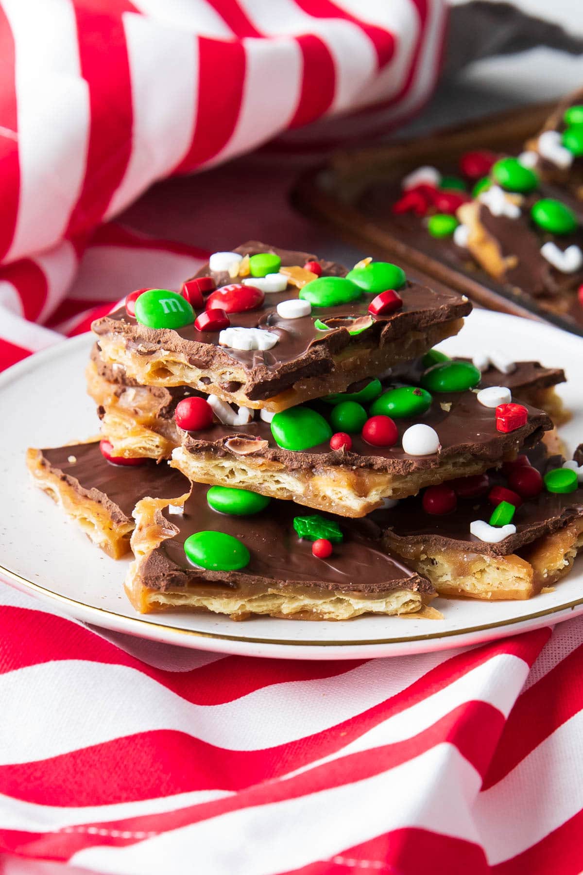 Stacks of Christmas crack recipe on a holiday plate with candy cane striped napkins