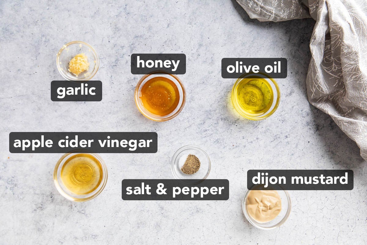 Honey Mustard Dressing recipe ingredients measured into prep bowls including honey, dijon mustard, olive oil, apple cider vinegar, garlic, and salt and pepper.