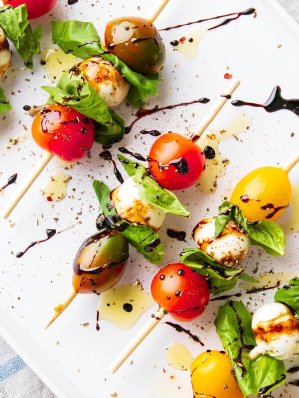 Close up of caprese skewers made with cherry tomatoes, mozzarella balls, and fresh basil.