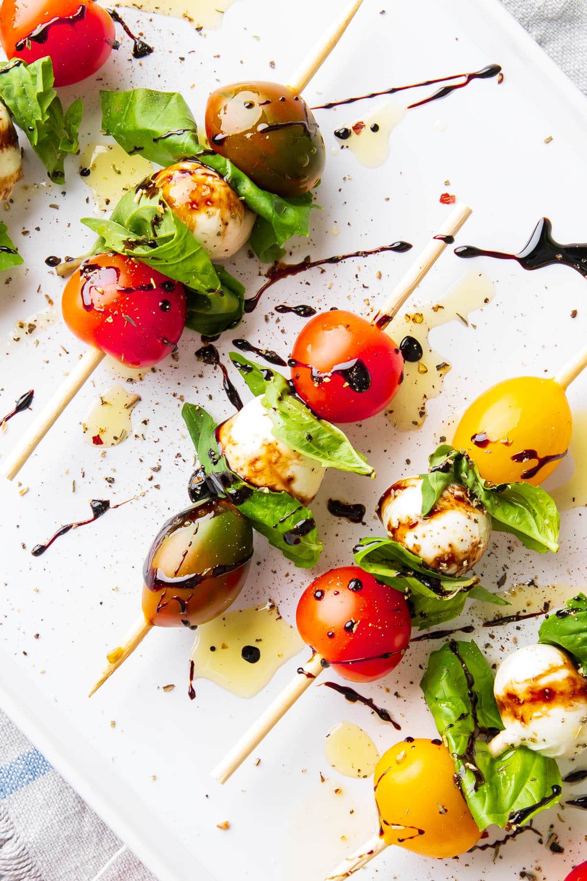 Close up of caprese skewers made with cherry tomatoes, mozzarella balls, and fresh basil.