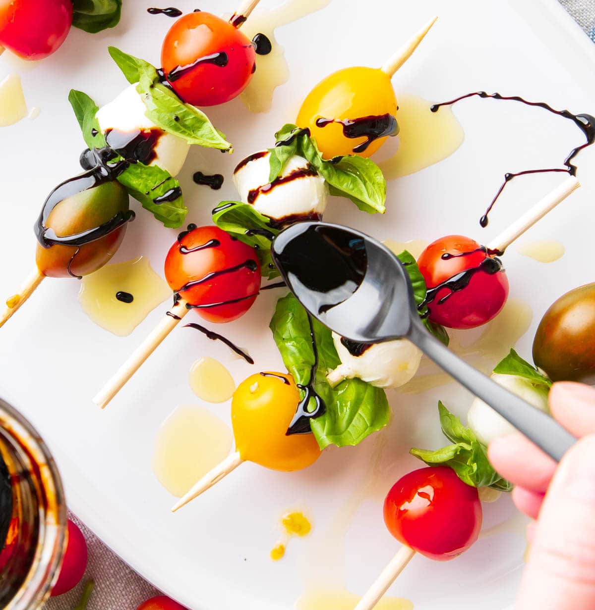 Spooning balsamic glaze over this caprese salad skewers recipe