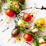 Close up of caprese skewers made with cherry tomatoes, mozzarella balls, and fresh basil.