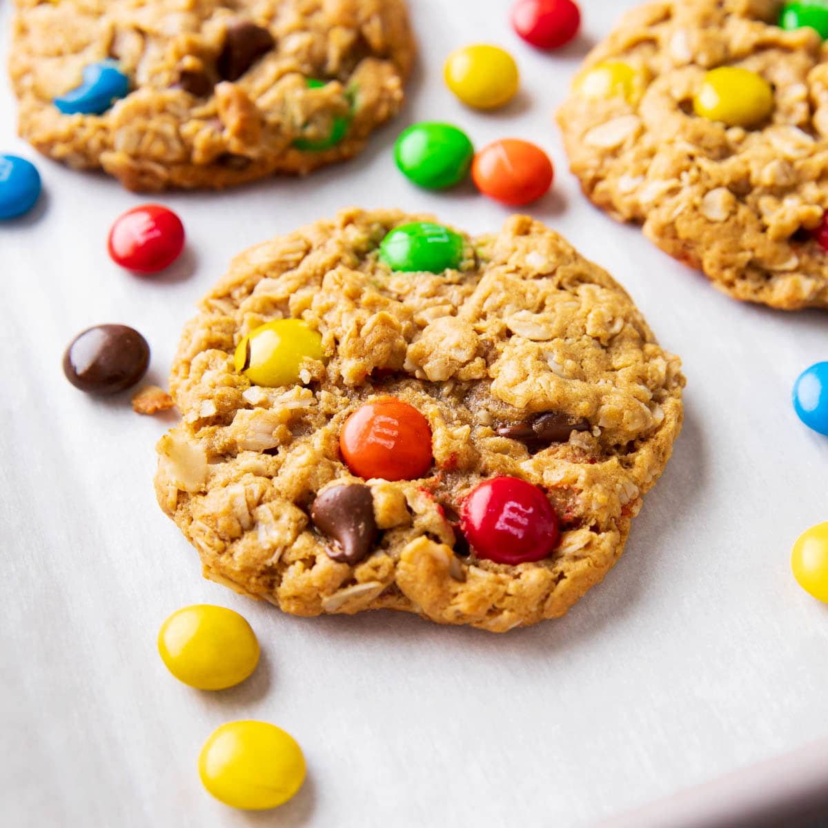 angled photo of monster cookies with chewy oat texture, dotted with colorful M&M’s candies and chocolate chips.