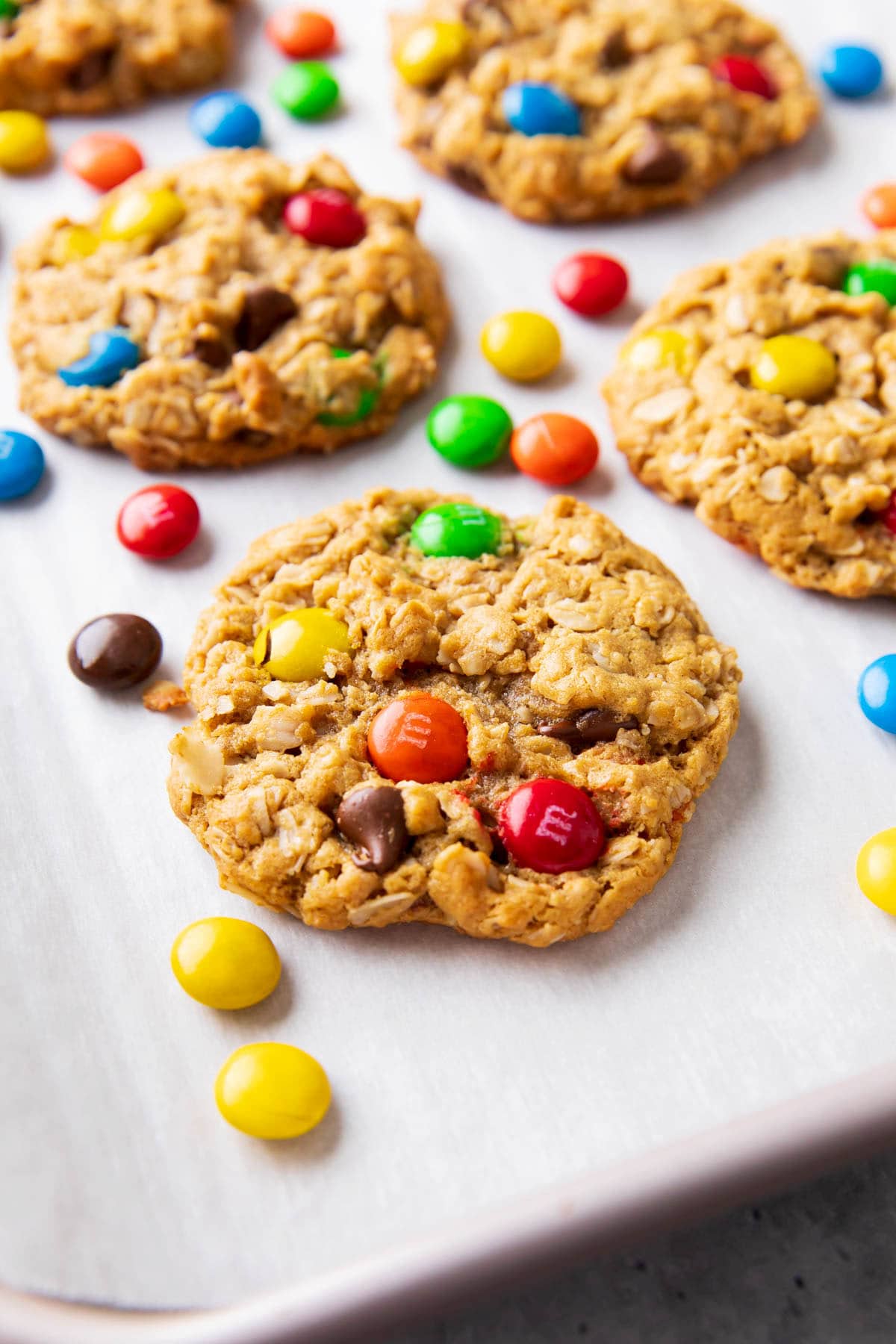 angled photo of monster cookies with chewy oat texture, dotted with colorful M&M’s candies and chocolate chips.