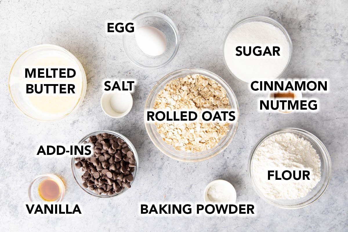 The ingredients for this Oatmeal Cookie Bars recipe in prep bowls, including oats, flour, cinnamon, egg, salt, butter, chocolate chips, sugar, vanilla extract, baking powder, and salt.