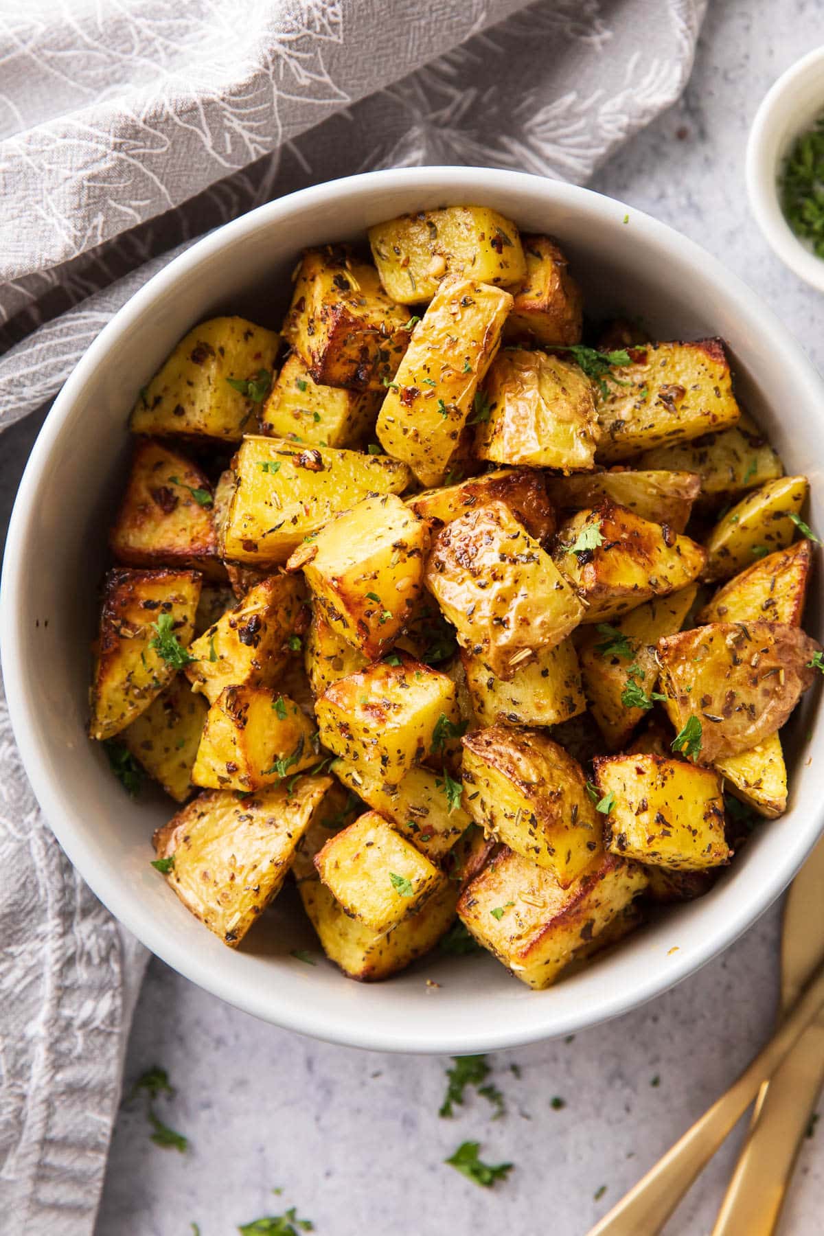 Air Fryer roasted potatoes in a serving bowl topped with seasoning and crisped edges