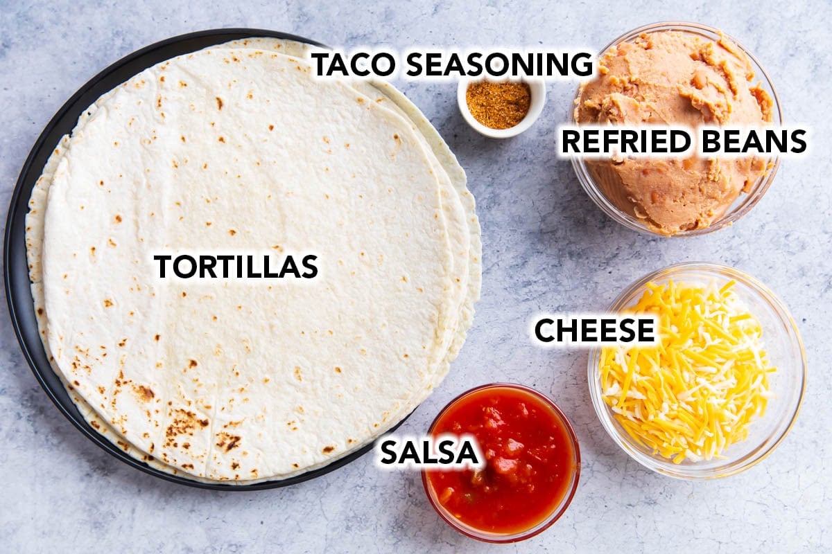 Ingredients for the best bean and cheese burrito recipe including flour tortillas, refried beans, cheese, taco seasoning, and salad