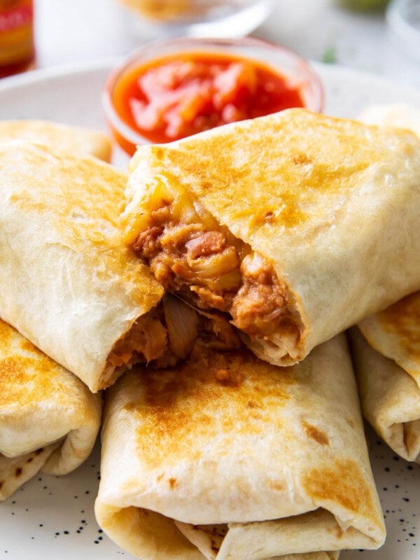 Close up of half of a bean and cheese burrito with refried beans and cheese oozing out.