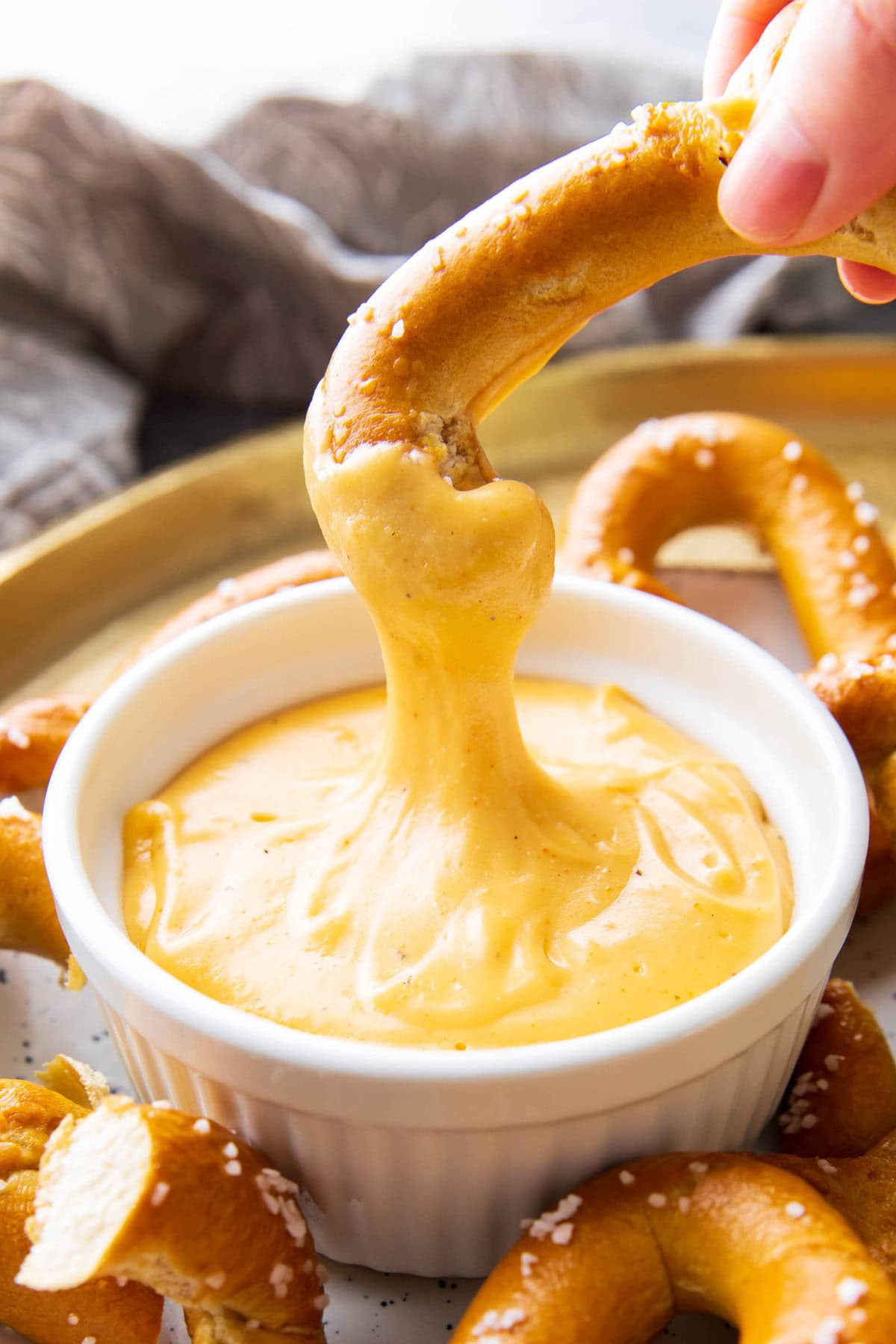 A hand dipping a pretzel into this beer cheese dip recipe for pretzels