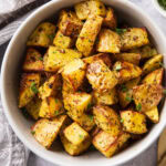 Air Fryer roasted potatoes in a serving bowl topped with seasoning and crisped edges