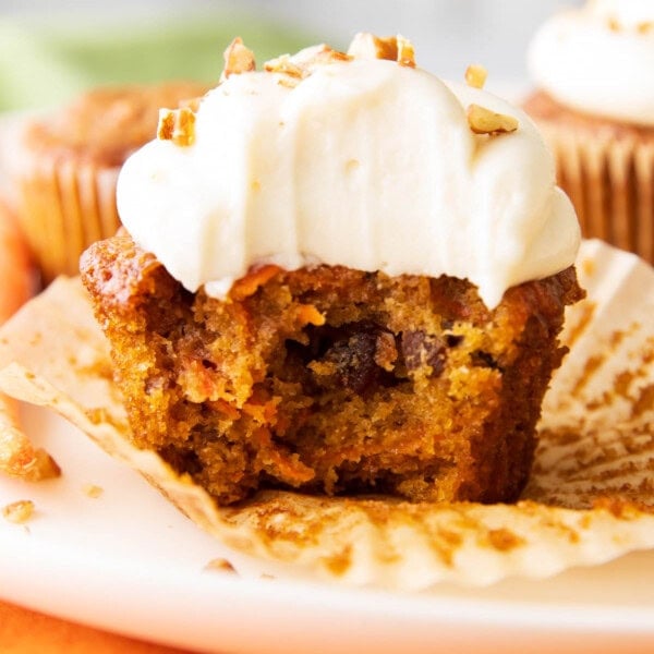 close up photo of the best carrot cake cupcakes with a bite taken out of it.