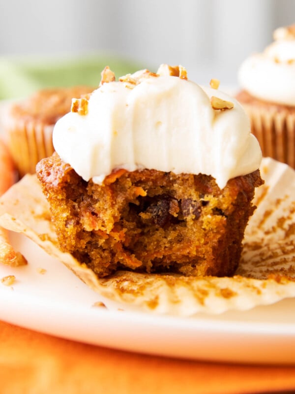 close up photo of the best carrot cake cupcakes with a bite taken out of it.