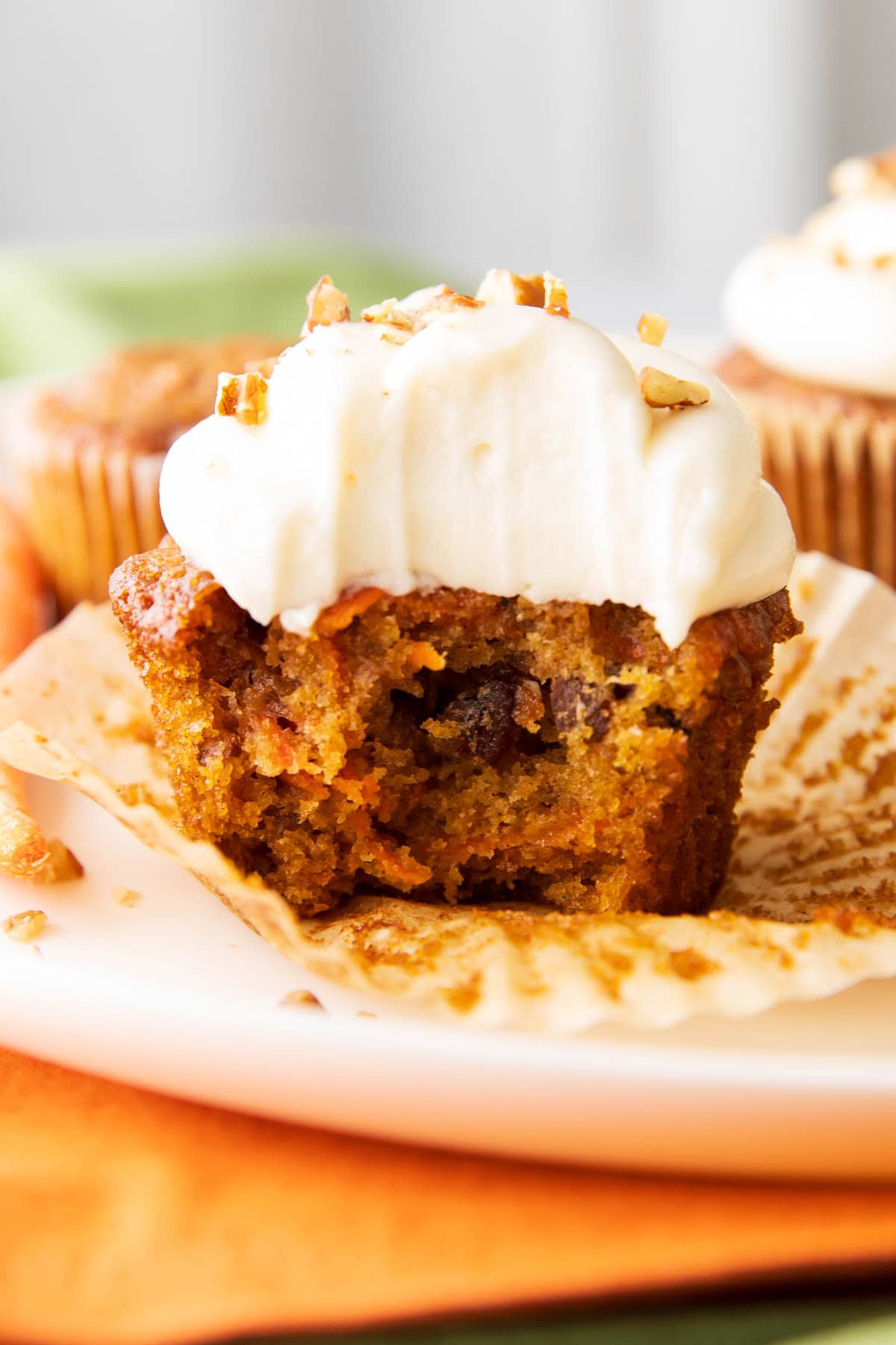 close up photo of the best carrot cake cupcakes with a bite taken out of it.