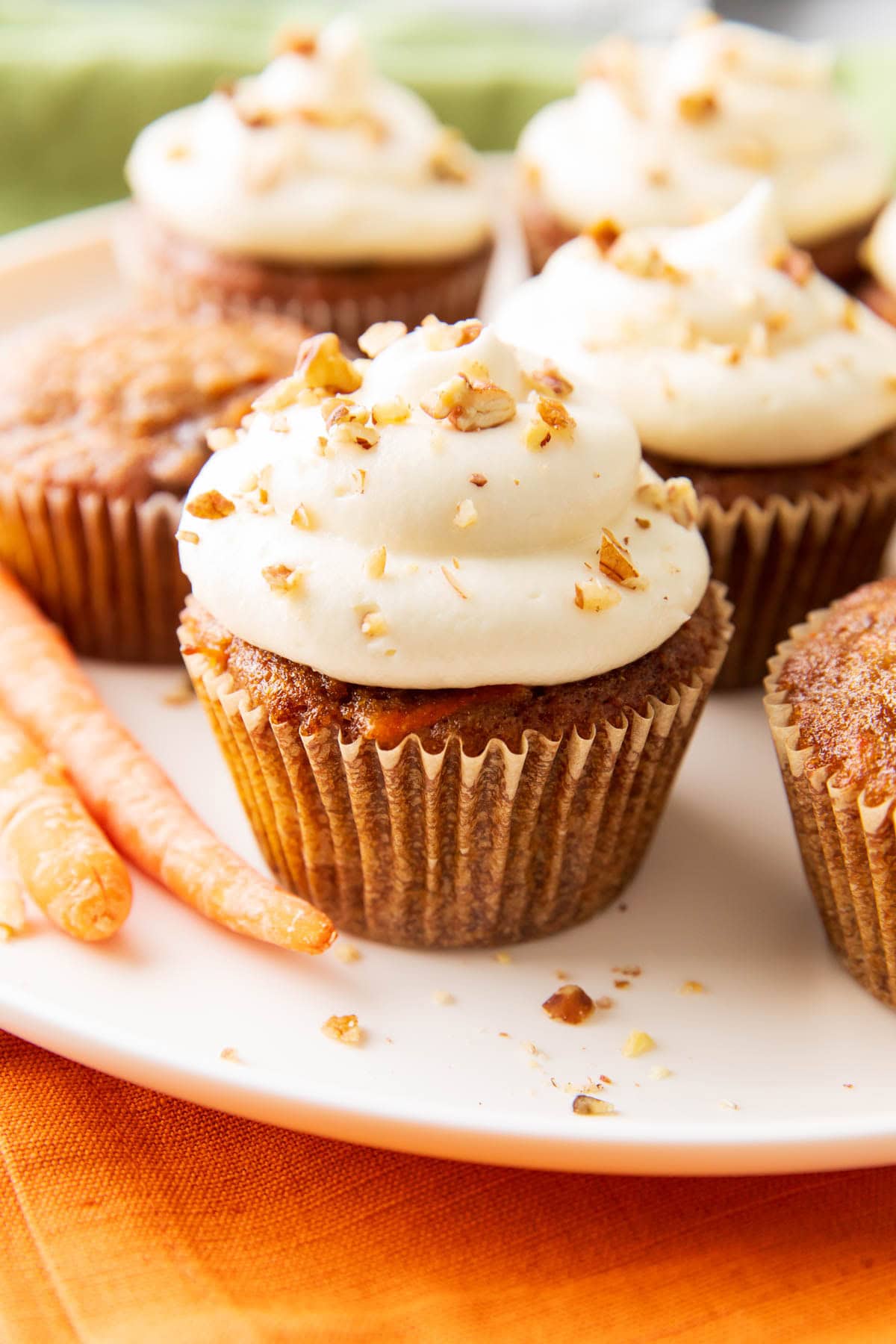 Easy homemade carrot cake cupcakes on a serving platter with carrots and lots of cream cheese frosting