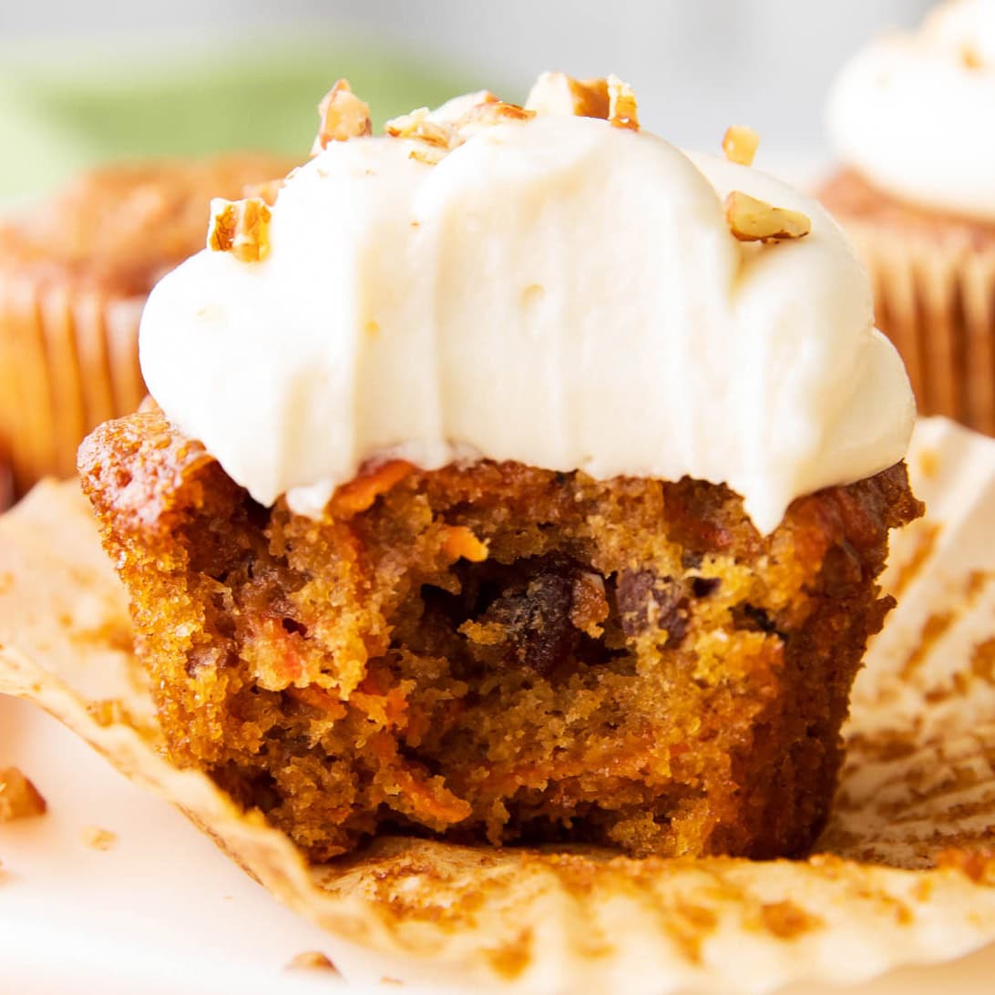 close up photo of the best carrot cake cupcakes with a bite taken out of it.