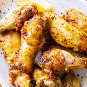 close up of Lemon Pepper Wings to show crispy skin, tender and juicy chicken with homemade sauce.