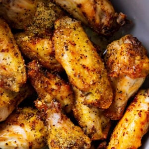 lemon pepper wings topped with lemon zest and pepper in a mixing bowl