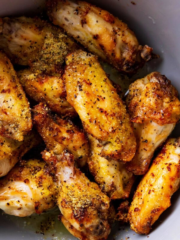 lemon pepper wings topped with lemon zest and pepper in a mixing bowl
