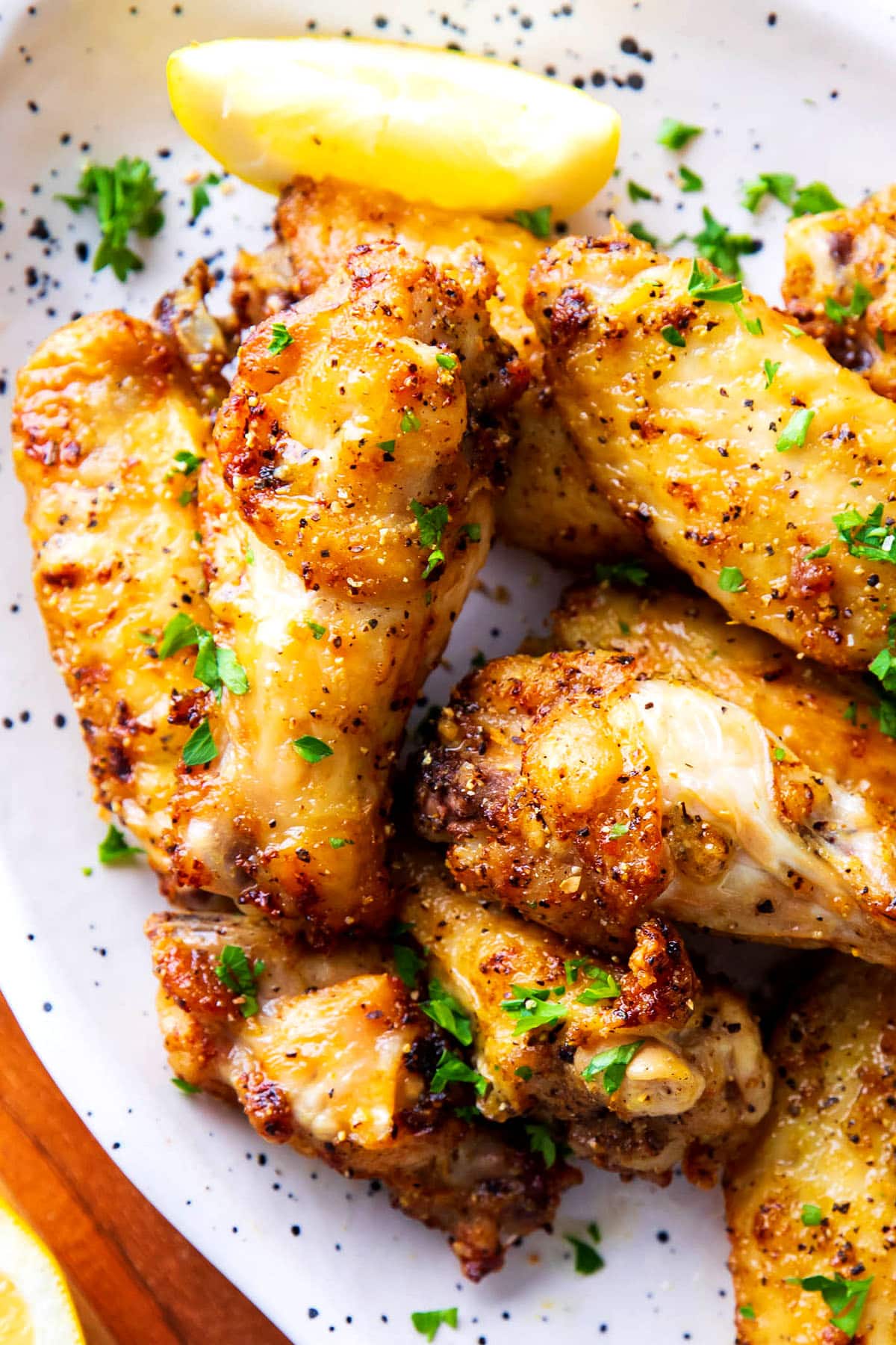 Lemon pepper wings with crispy skin, zesty lemon, butter, and fresh parsley garnish.