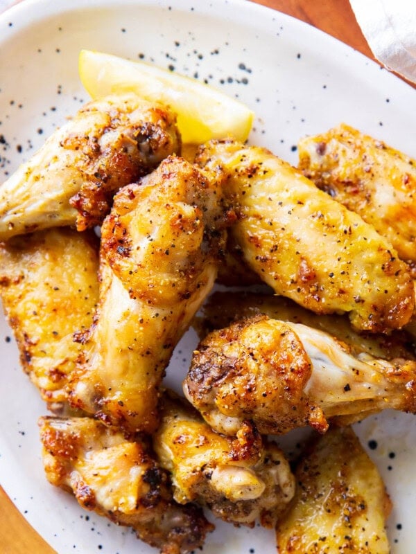 close up of Lemon Pepper Wings to show crispy skin, tender and juicy chicken with homemade sauce.