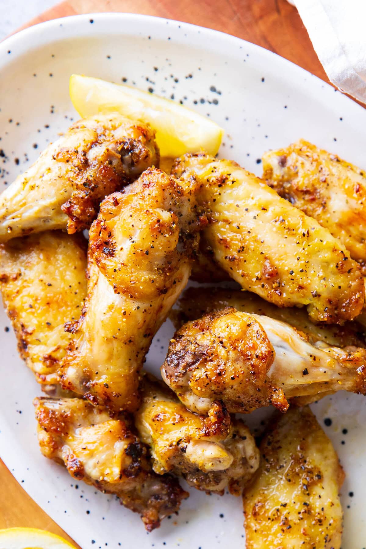 close up of Lemon Pepper Wings to show crispy skin, tender and juicy chicken with homemade sauce.