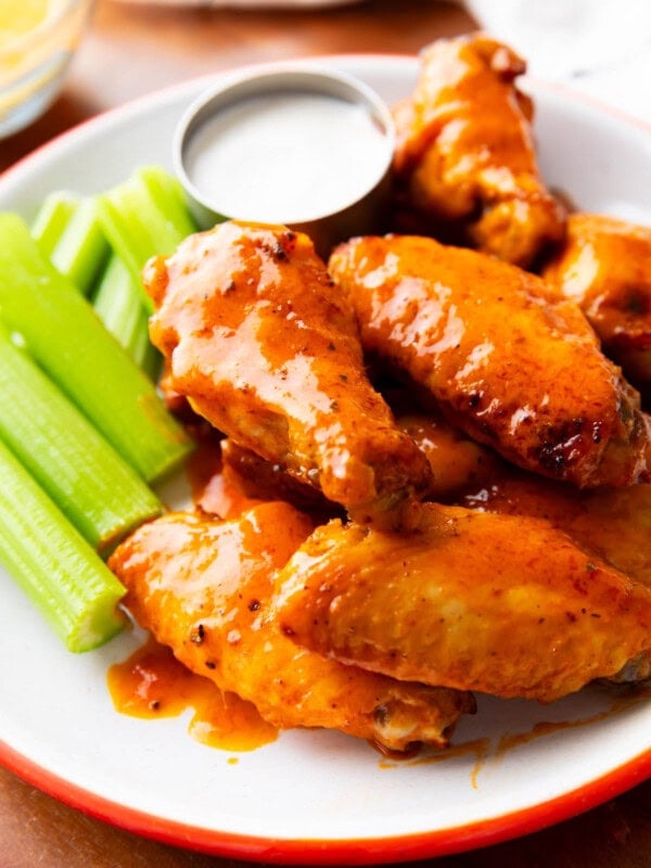 Air fryer buffalo wings served on a plate with celery sticks and ranch dressing.