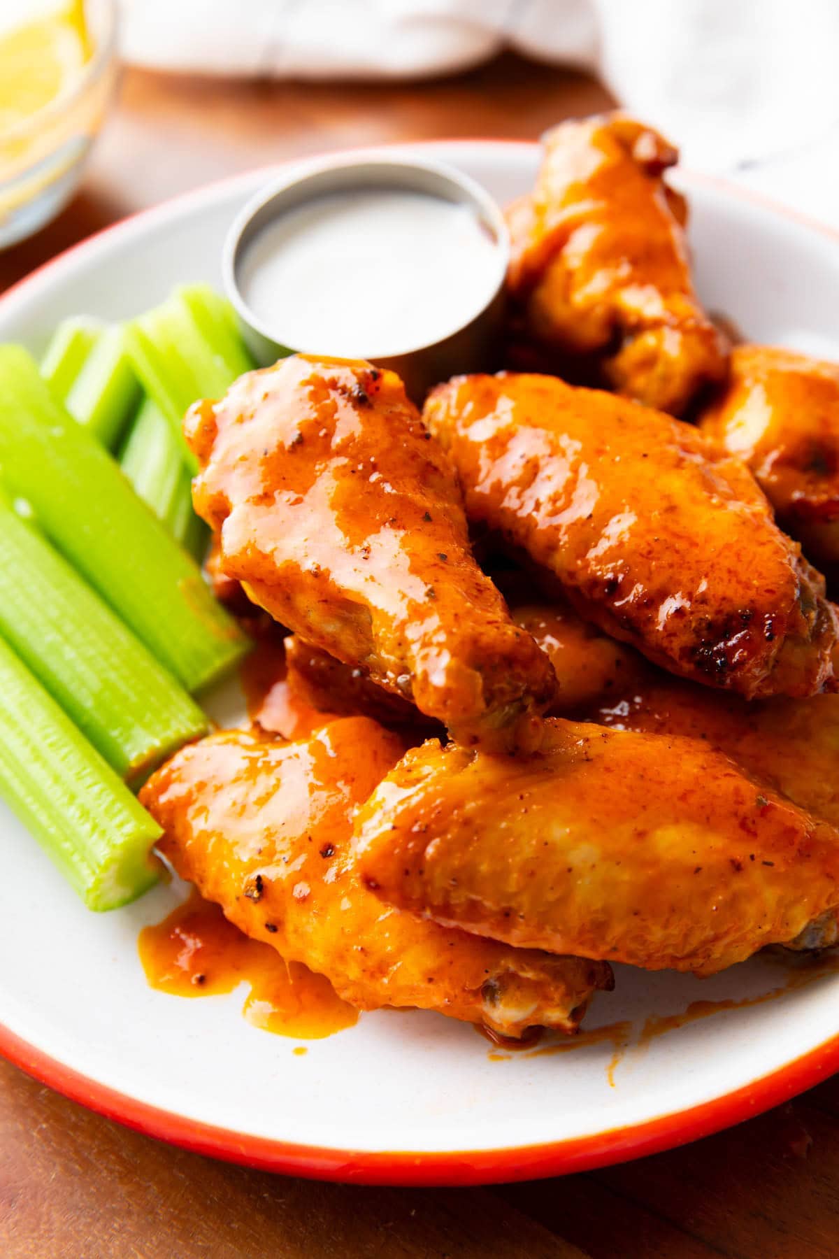 Air fryer buffalo wings served on a plate with celery sticks and ranch dressing.