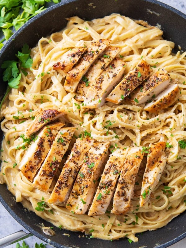 This chicken fettuccine Alfredo recipe in a skillet topped with roasted herby chicken, velvety creamy Alfredo sauce, and oodles of fettuccine pasta.