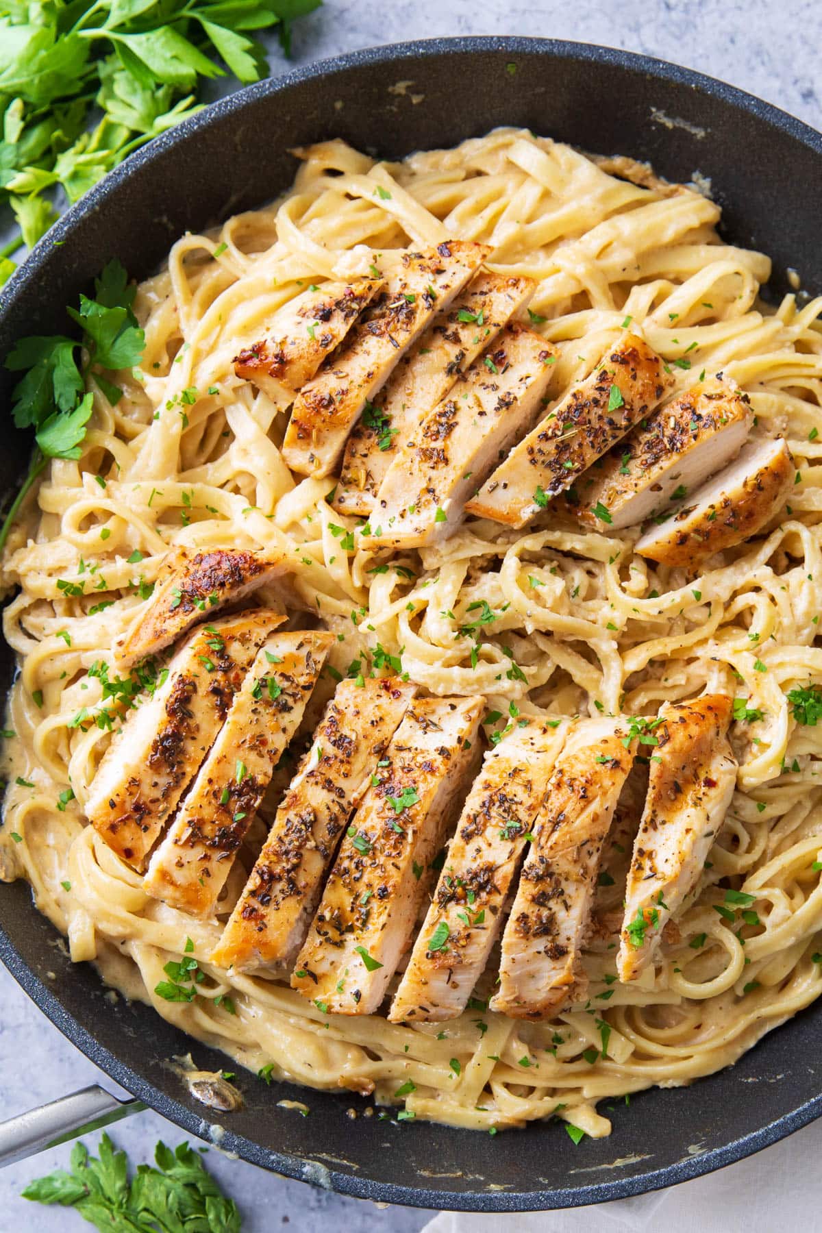 This chicken fettuccine Alfredo recipe in a skillet topped with roasted herby chicken, velvety creamy Alfredo sauce, and oodles of fettuccine pasta.