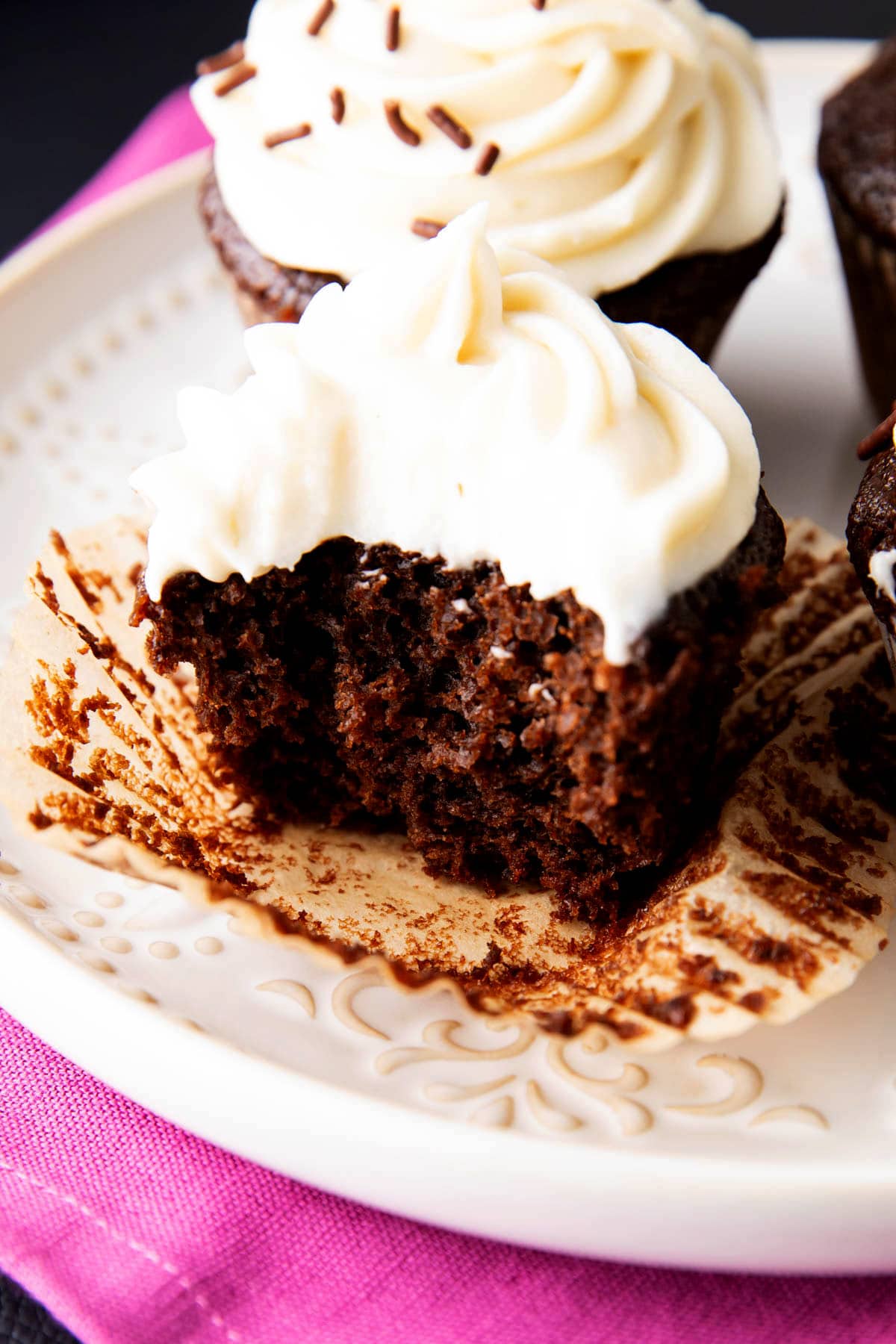 A half eaten cupcake shows the tender, moist crumb inside.