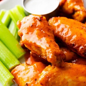 Air fryer buffalo wings served on a plate with celery sticks and ranch dressing.