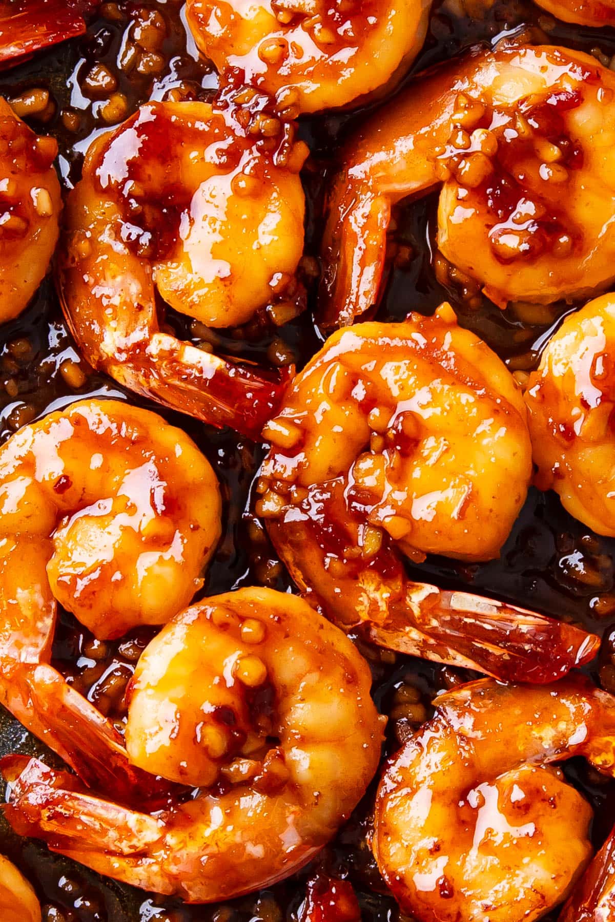 Close up of the spicy sweet sauce coating this Asian garlic shrimp recipe with tender bits of garlic and chili.